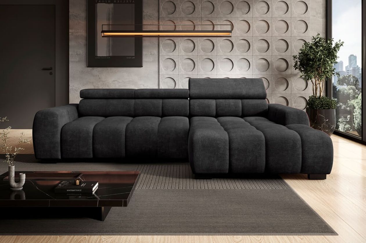Großes schwarzes Ecksofa mit gesteppter Polsterung und verstellbaren Kopfstützen in einem modernen Wohnraum mit strukturierter Betonwand und warmem Holzboden.