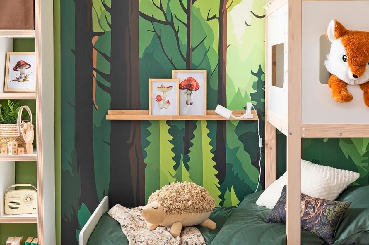 Kinderzimmer mit Waldmotivtapete, einem Regal mit Pilzbildern, einem Stoffigel auf dem Bett und einem Plüschfuchs, der an einem Hochbett hängt.