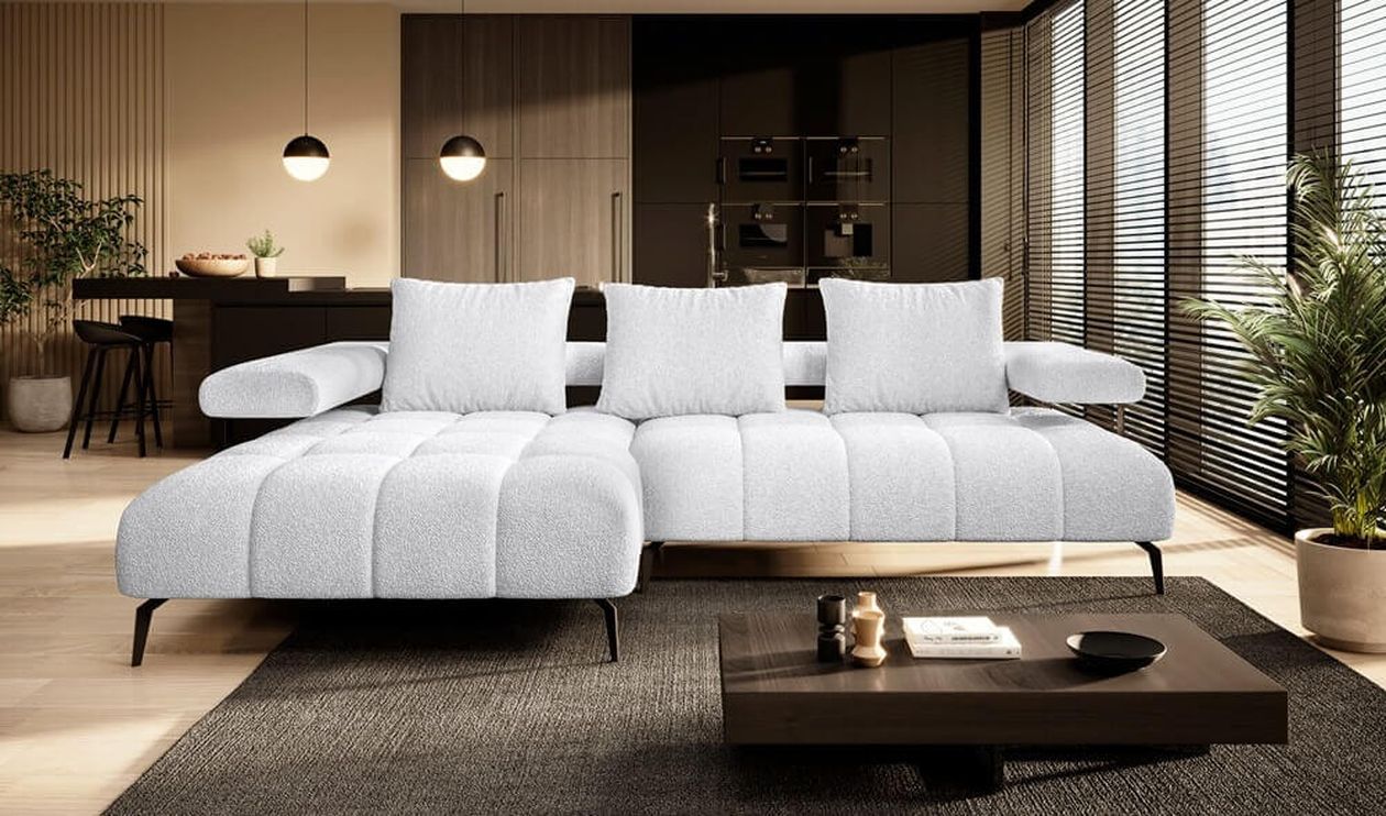 Modernes Wohn-Ess-Zimmer mit einem großen weißen Bouclé-Ecksofa mit Récamiere links und schwarzen Metallfüßen. Im Hintergrund eine offene Küche mit dunklen Holzfronten. Davor ein niedriger dunkler Couchtisch, ein grauer Teppich und Kugel-Pendelleuchten.