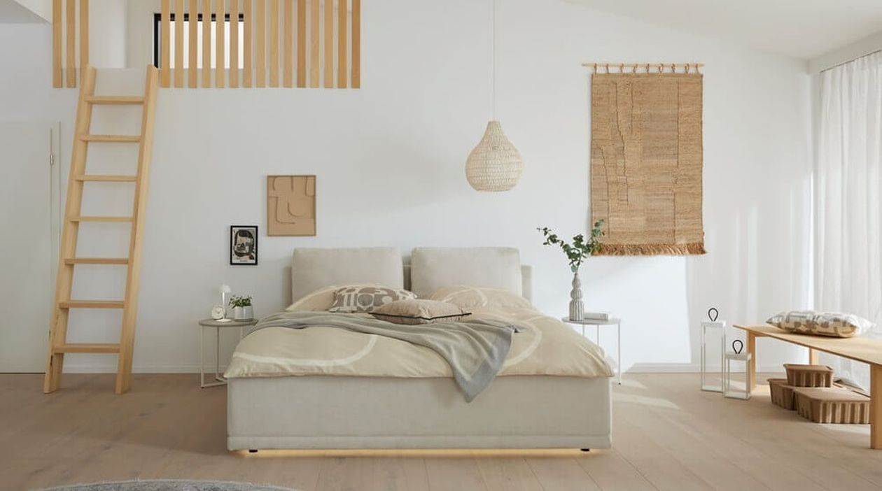 Cremefarbenes Polsterbett mit gepolstertem Kopfteil in einem hellen, minimalistischen Schlafzimmer mit Holzleiter zur Galerie, Pendelleuchte und natürlicher Wanddekoration.