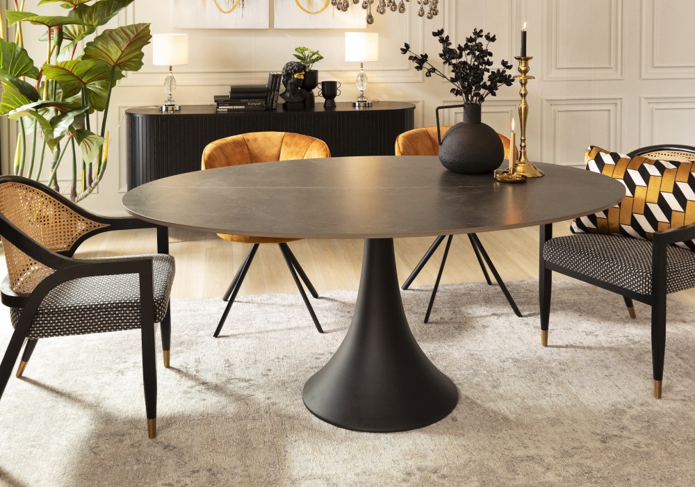 Moderner Essbereich mit einem runden schwarzen Tisch, vier stilvollen Stühlen und dekorativen Gegenständen. Pflanzen und Lampen verstärken die elegante Atmosphäre.