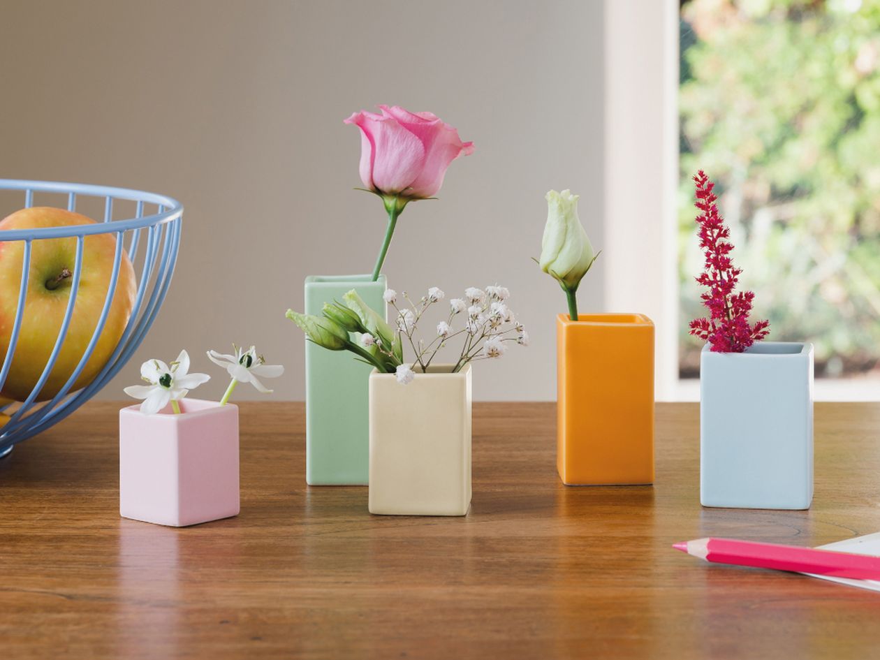 Das fünfteilige, in Pastellfarben gehaltenen Vasenset Mini von Remember steht auf einem Holztisch. Die zylindrischen Vasen sind mit verschiedenen Blumen gefüllt.