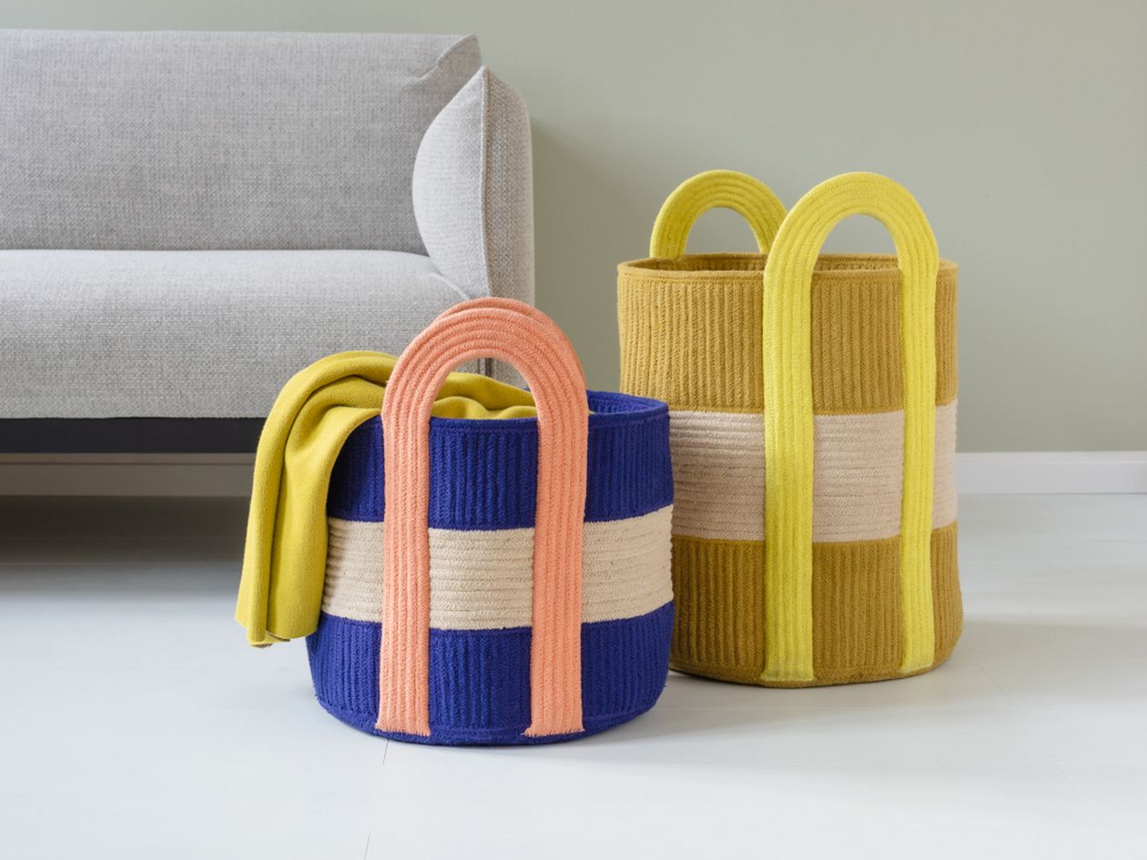 Ein blauer und ein gelber Baumwollkorb des Modells Colombo aus dem Hause Remember stehen vor einem Skandi-Sofa..