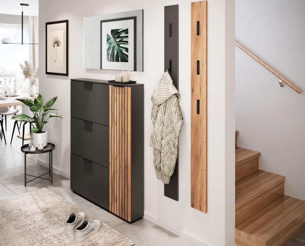 Moderner Eingangsbereich mit einem schwarzen Schuhschrank, Garderobenhaken und einem Blick in einen hellen Essbereich.