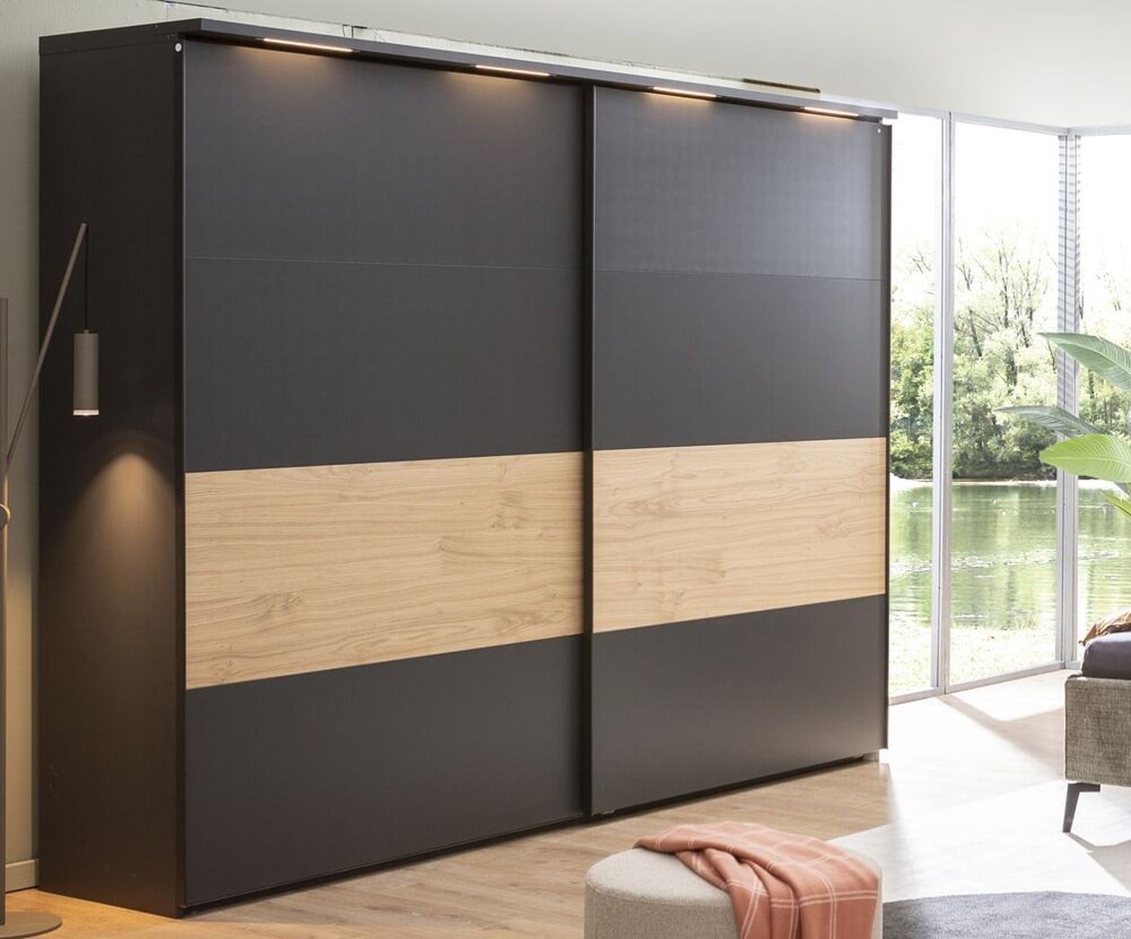 Großer Schwebetürenschrank mit schwarzer und holzfarbener Front, oben mit integrierter LED-Beleuchtung.