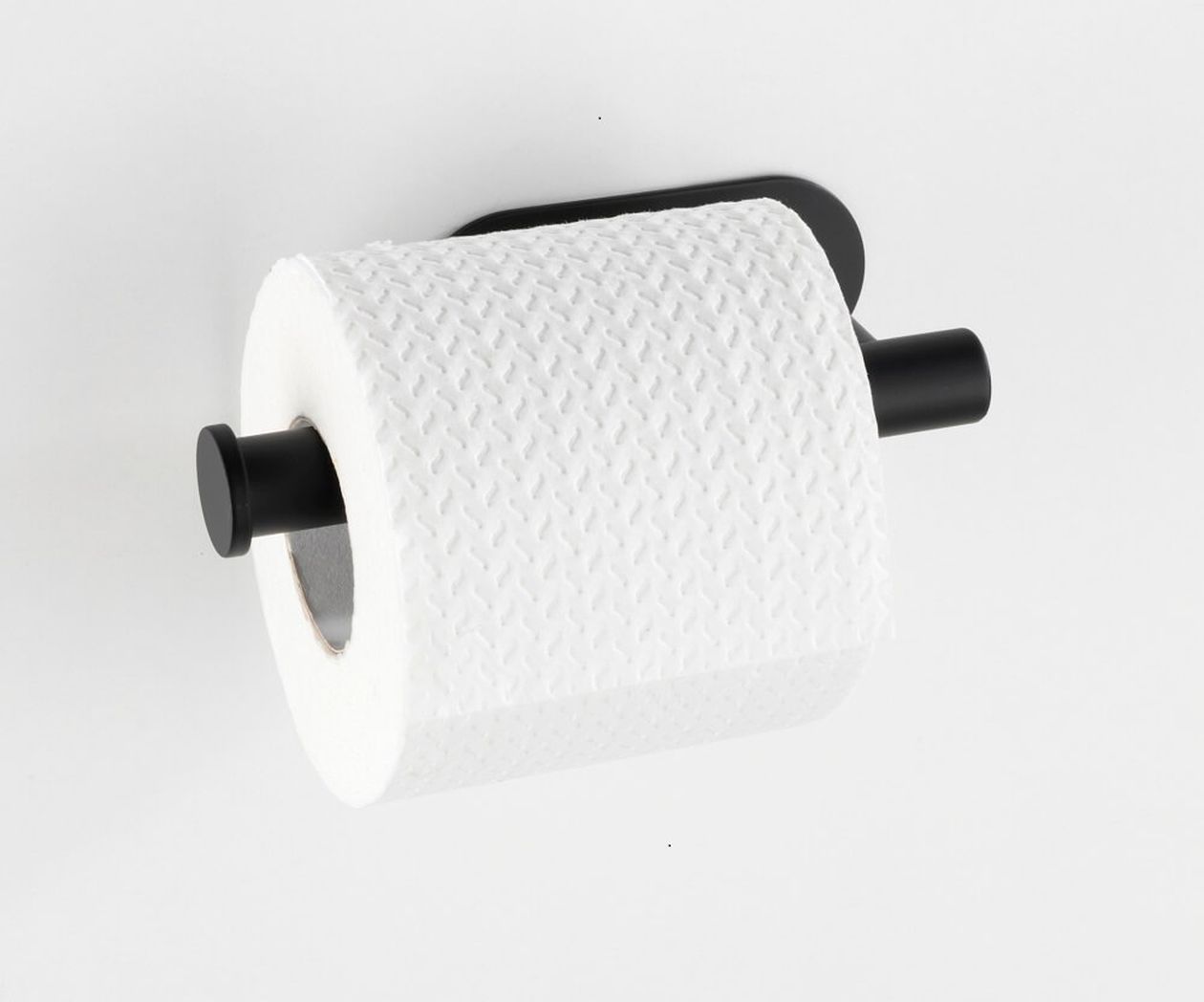 Eine Rolle strukturiertes weißes Toilettenpapier in einem eleganten, schwarzen Wandhalter vor einem schlichten weißen Hintergrund.