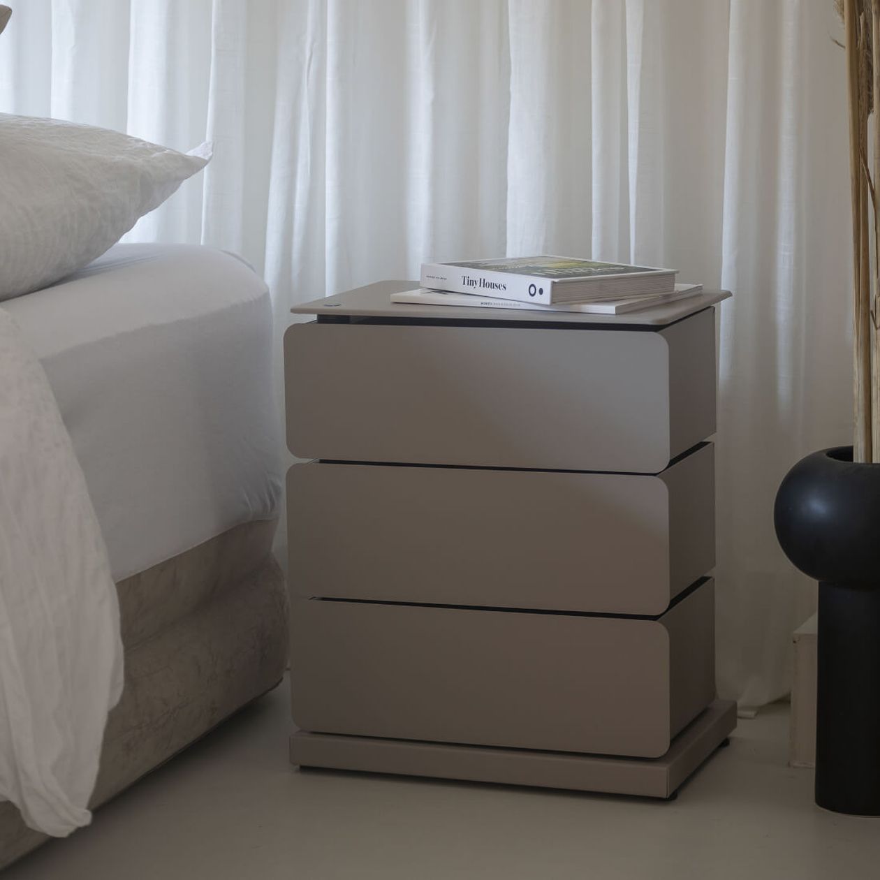 Kommode mit Schubladen in einem bräunlichen Grauton. Darauf Bücher.