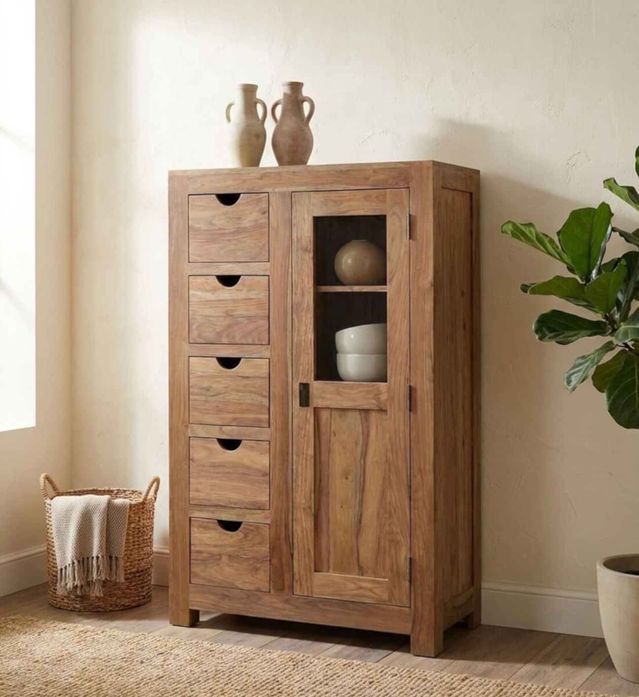 Holzschrank mit fünf Schubladen und einer Glastür, in dem Töpferwaren aufbewahrt werden. Korb und grüne Pflanze auf beiden Seiten, vor einer hellen Wand.