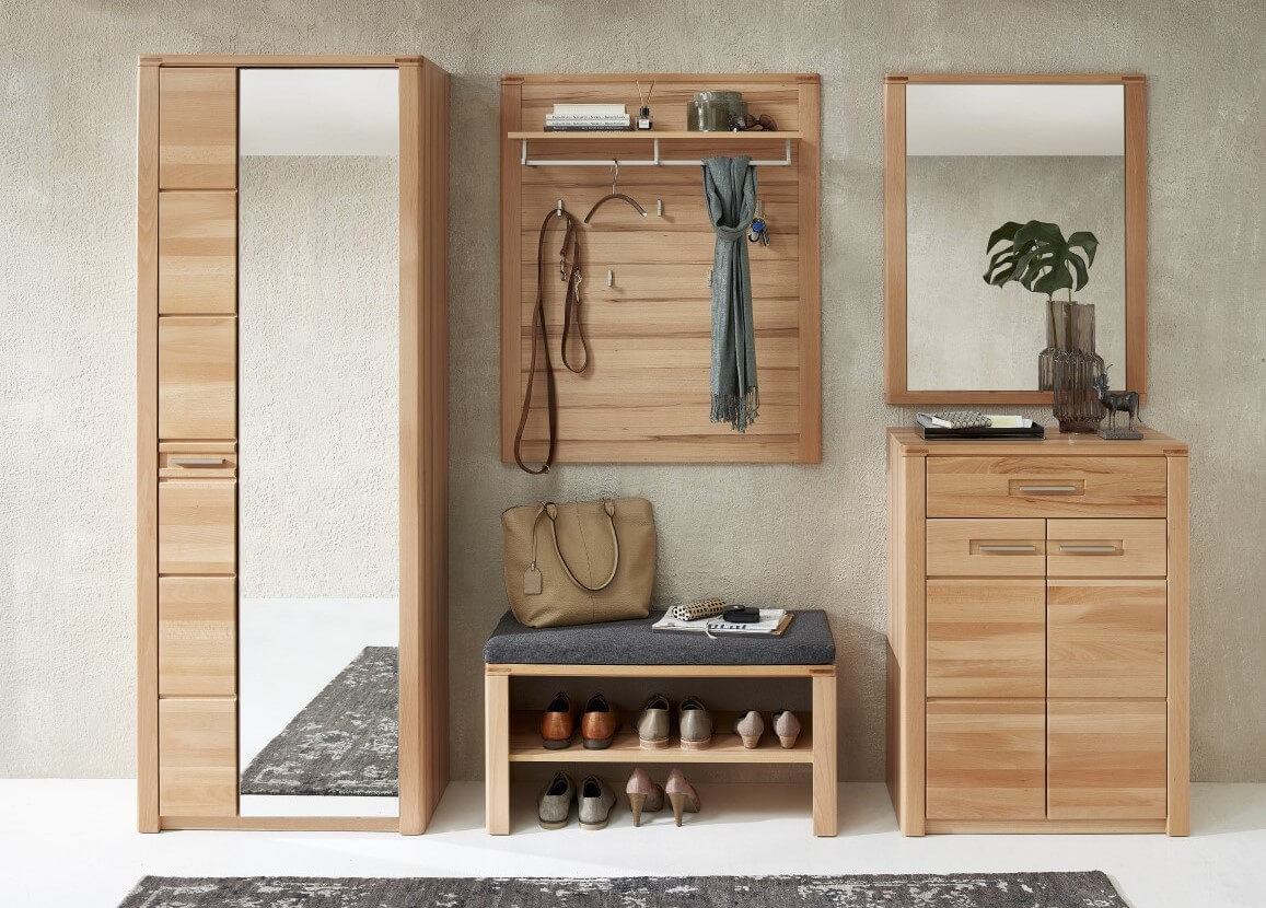 Holzflur mit einem hohen Spiegelschrank, Wandhaken, einer Bank mit Schuhen darunter und einer Kommode mit einem Spiegel darüber.