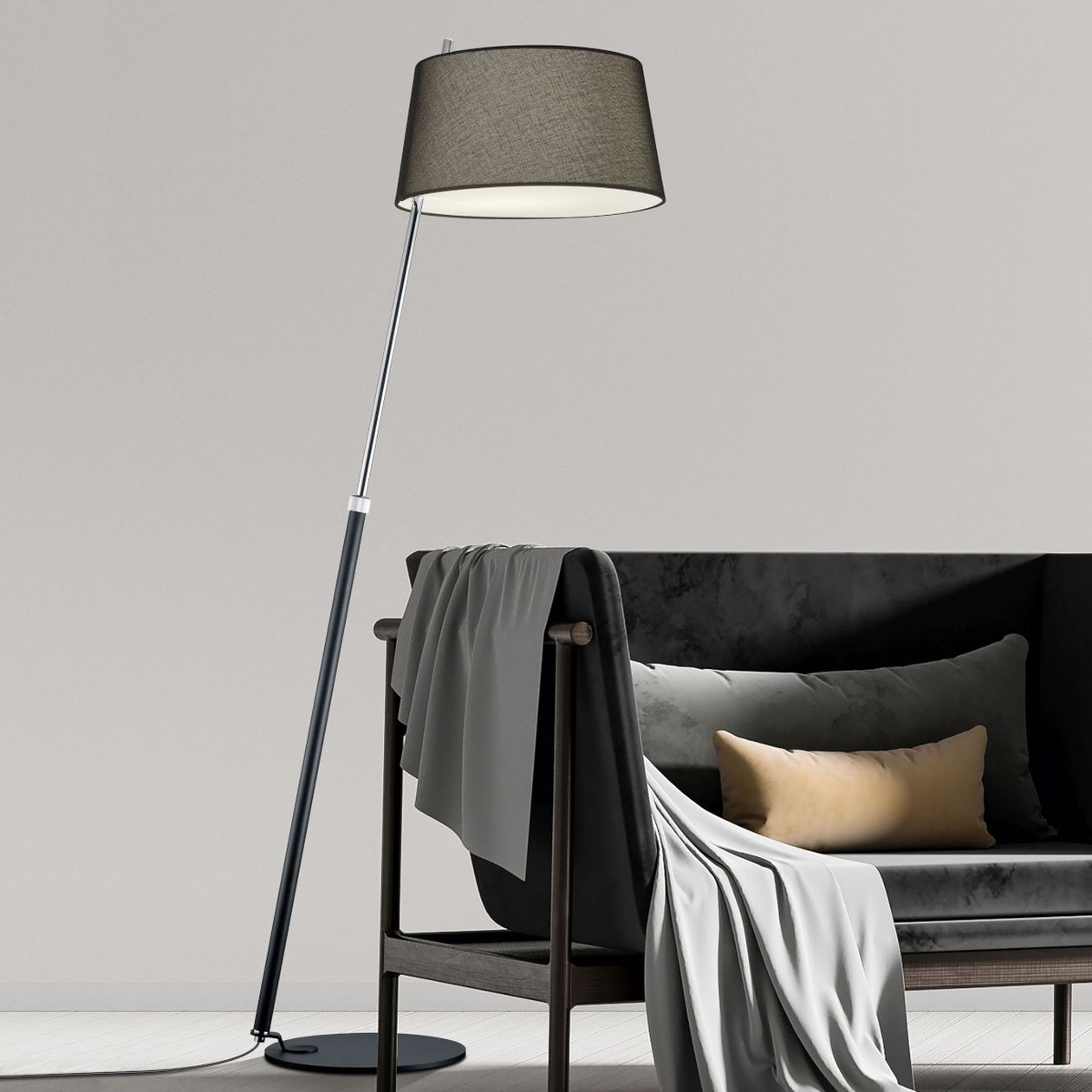 Eine hohe Stehlampe der Marke Hell mit grauem steht hinter einem schwarzen Sofa mit Holzgestell.