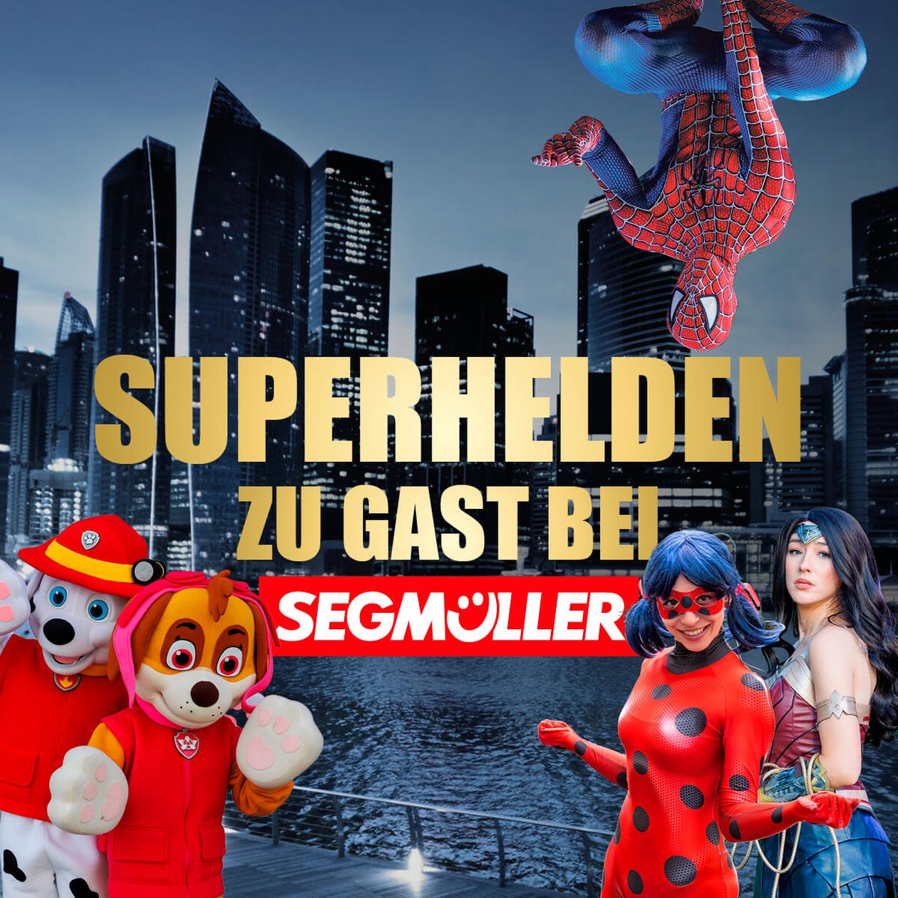 Kostümierte Charaktere, darunter bekannte Superhelden und tierische Figuren, posieren vor einer Stadtsilhouette. Text: "Superhelden zu Gast bei Segmüller".
