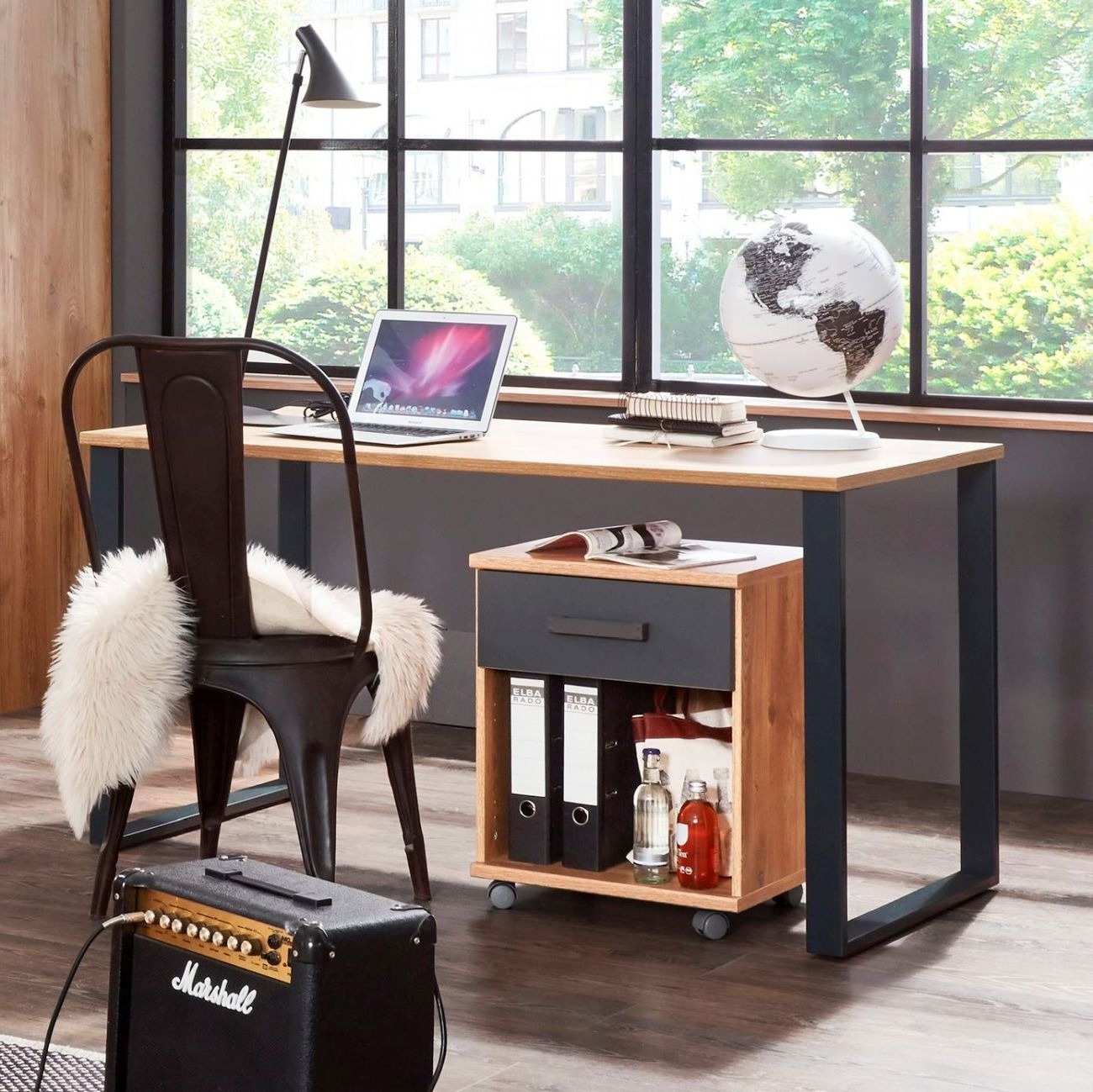 Auf dem Foto befindet sich ein Jugendschreibtisch mit brauner Holzplatte und schwarzem Metallgestell. Außerdem stehen darunter ein passender Rollcontainer und davor ein schwarzer Metallstuhl.