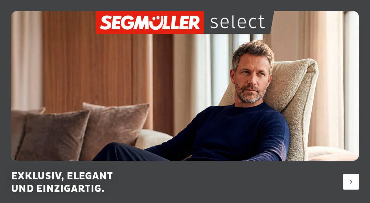 Ein Mann in einem blauen Pullover sitzt bequem auf einem beigen Stuhl. Die Select-Werbung wirbt mit Exklusivität und Qualität.