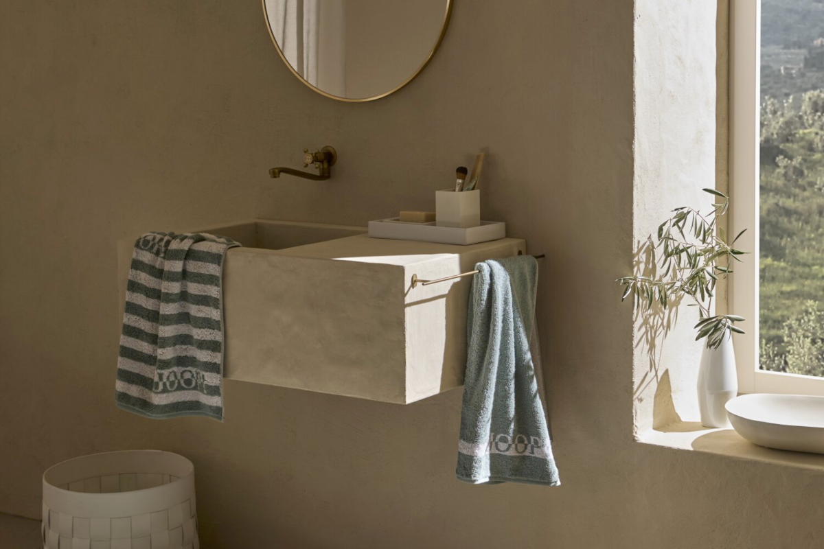 Helles, mediterranes Badezimmer mit Hängewaschbecken und dem grün-weiß gestreiften Badteppich Split