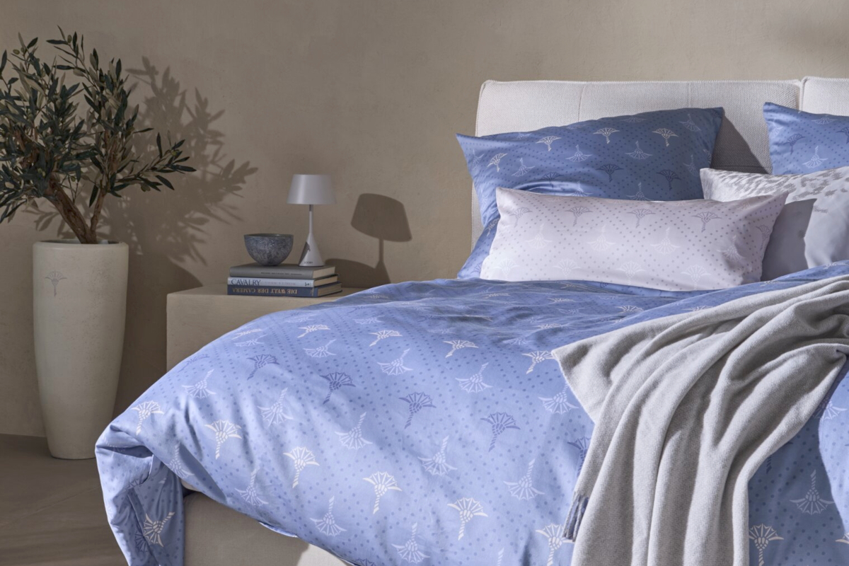 Helles, mediterranes Schlafzimmer mit der Bettwäsche Cornflower Charm in Blau mit dem typischen Muster der Marke JOOP!