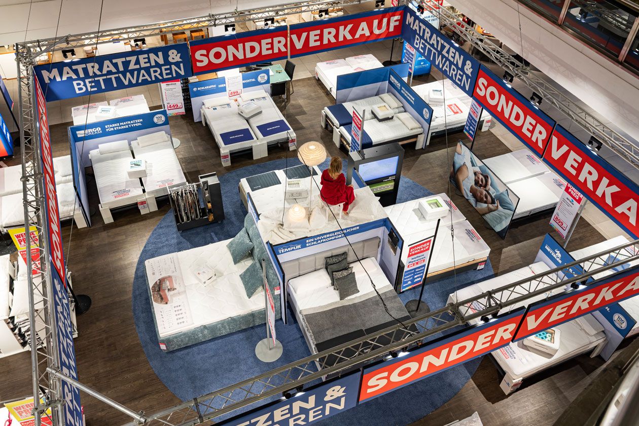 Blick von oben auf den Matratzen & Bettwaren Sonderverkauf im Lichthof eines SEGMÜLLER Einrichtungshauses.