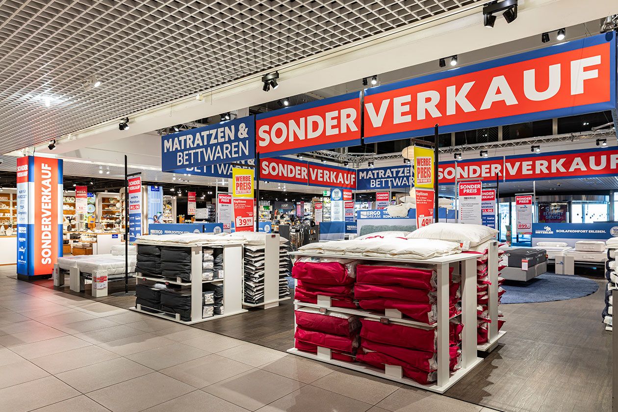 In Stapeln angeordnete Bettwaren auf der Ausstellungsfläche des SEGMÜLLER Matratzen & Bettwaren Sonderverkaufs.