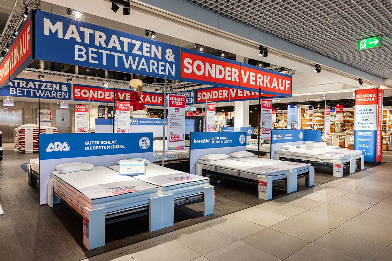 Ausstellungsfläche des SEGMÜLLER Matratzen und Bettwaren Sonderverkaufs mit drei Doppelbetten und verschiedenen Matratzen.