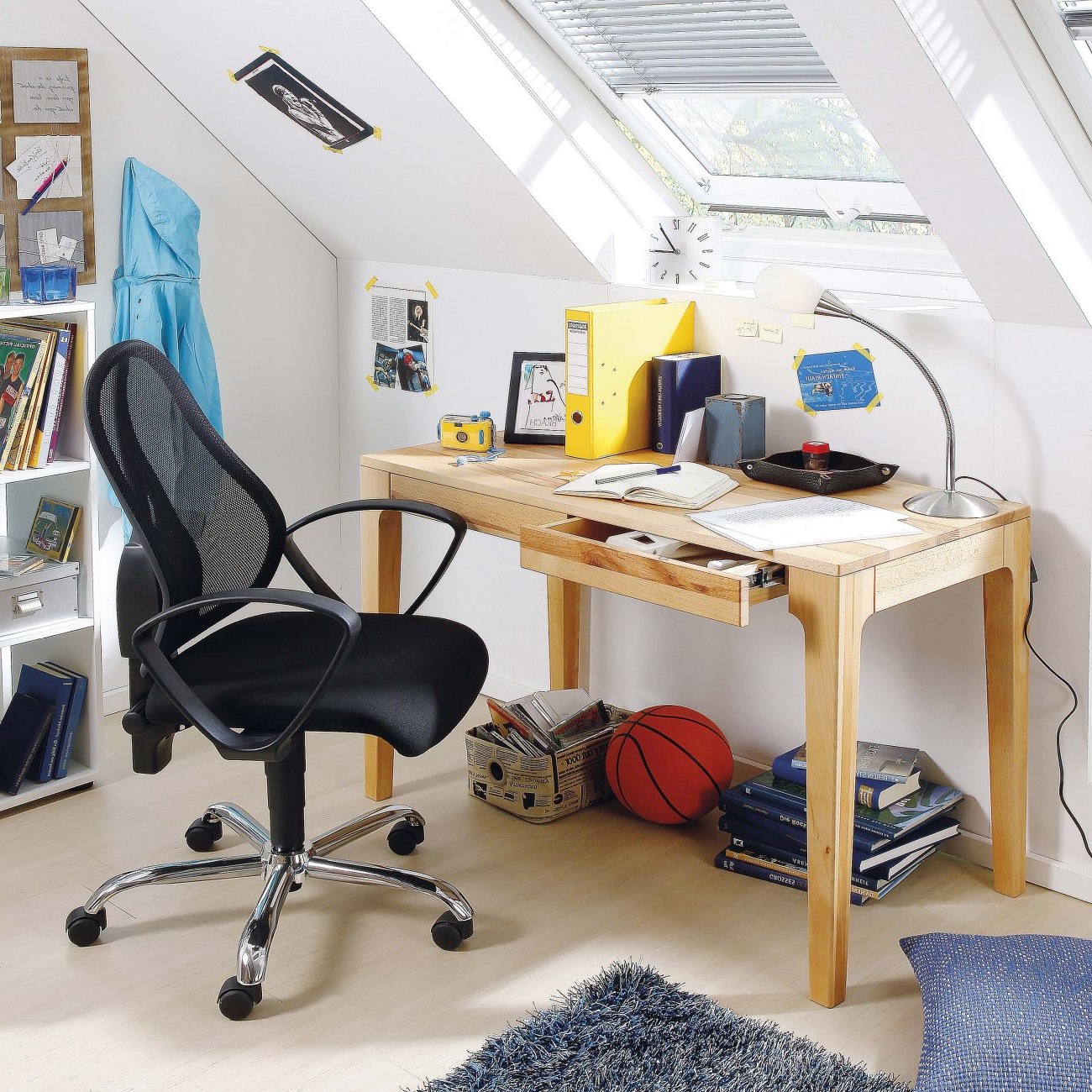 Auf dem Foto befindet sich ein Jugendschreibtisch aus Holz mit zwei Schubladen. Davor befindet sich ein schwarzer Bürostuhl.