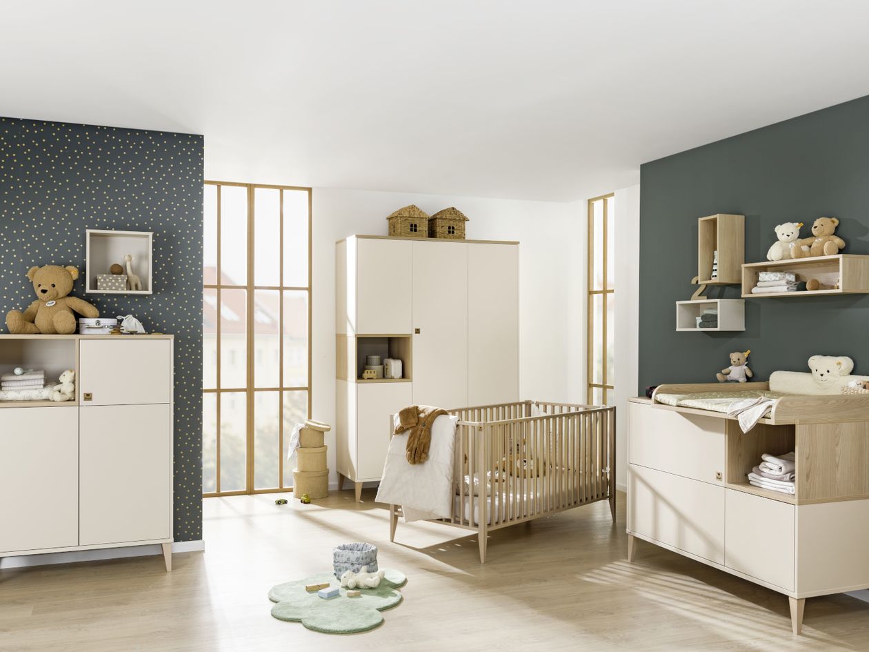 Ein Babyzimmer mit petrolfarbenen Wänden, eingerichtet mit den beigen Möbeln der Paidi Serie Mila & Ben mit Elementen mit Melaminharzfolie im Stil Skandinavian Wood.