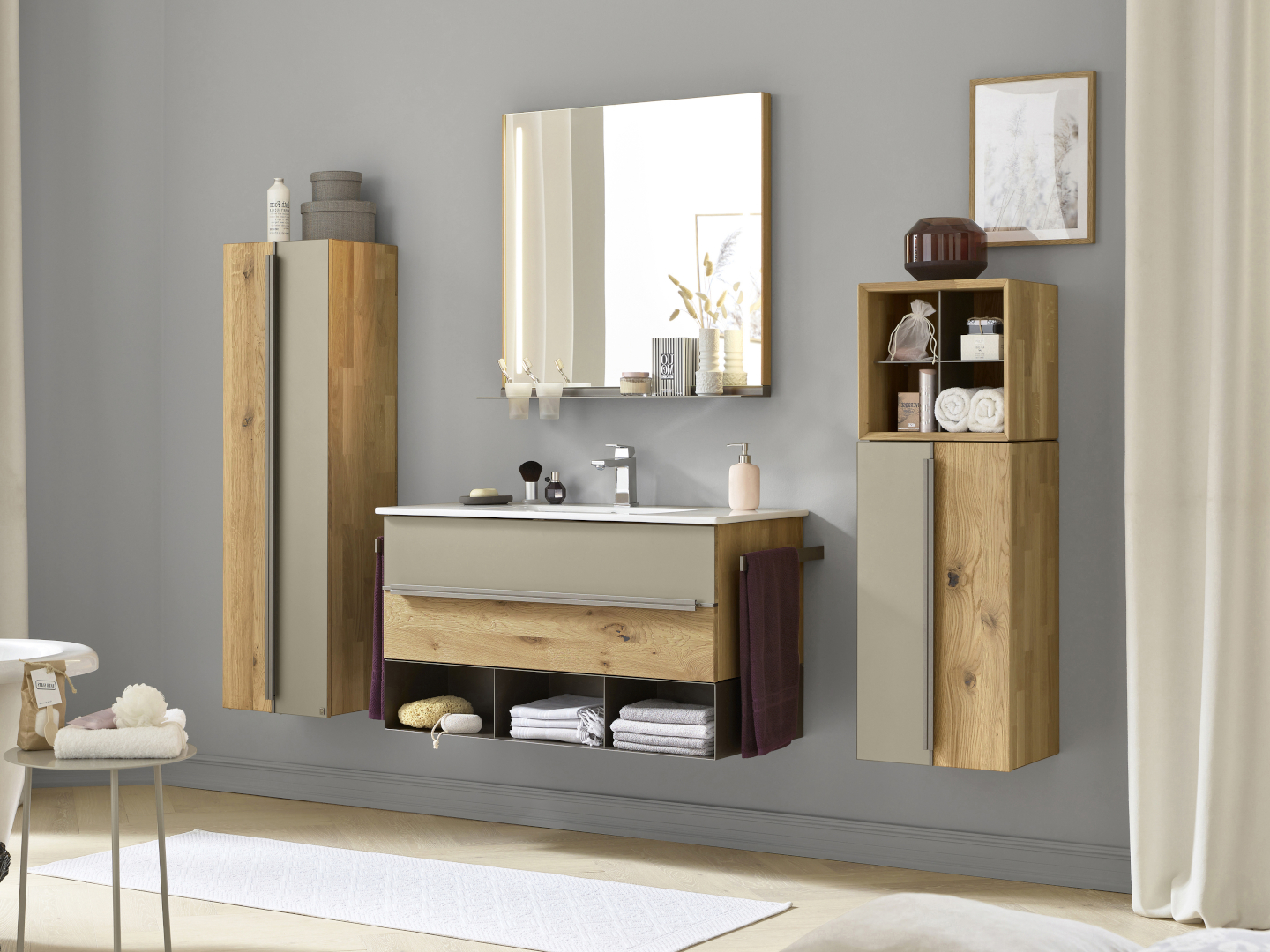 Ein Badezimmer mit wandhängenden Möbeln der Musterring-Serie Jarin mit Fronten aus Colorglas in der Farbe Titan und weiteren Elementen aus massiver Wildeiche