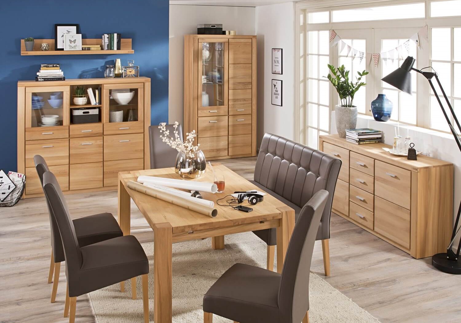 Vitrine Tabea in mit heller Kernbuche eingerichtetem Esszimmer. Dazu gehört Tisch mit Stühlen, eine Kommode und ein Highboard.