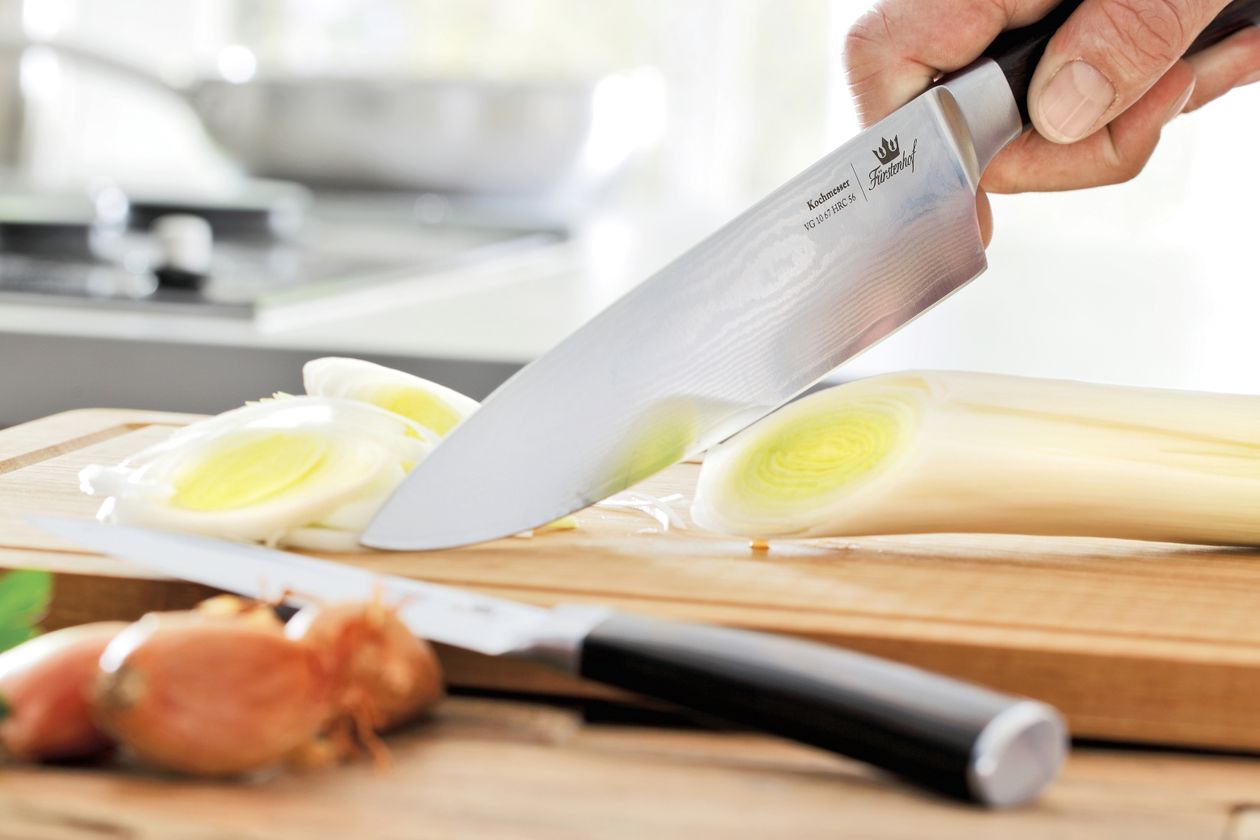 Das Kochmesser Damaststahl von Fürstenhof schneidet einen Lauch.