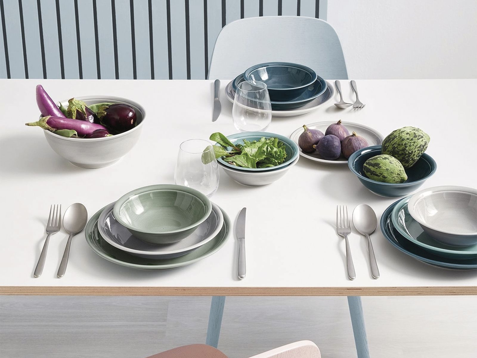 Auf einem weißen Tisch sind Schüsseln und Teller der Serie Trend White & Colour der Marke Thomas aus Porzellan in den Farben Weiß, Moss und Night platziert. Befüllt sind einige davon mit Gemüse und Früchten.