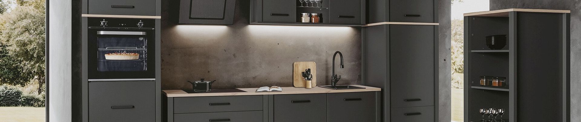 Moderne Küche mit dunklen Schränken, eingebautem Backofen, Dunstabzugshaube, Spüle und beleuchteten Regalen.