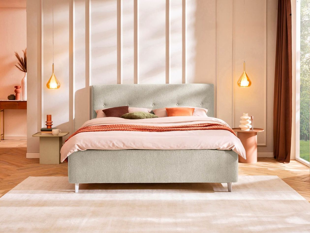 Modernes Schlafzimmer mit Polsterbett, warmen Farben und zwei Hängeleuchten links und rechts vom Bett.