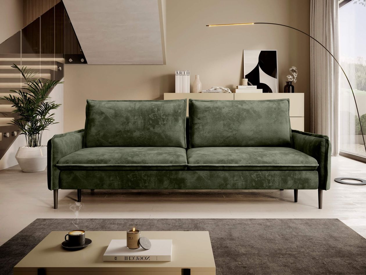 Modernes, grünes Schlafsofa in wohnlichem Ambiente, frontal fotografiert, mit Kaffee und Kerze auf dem Tisch.