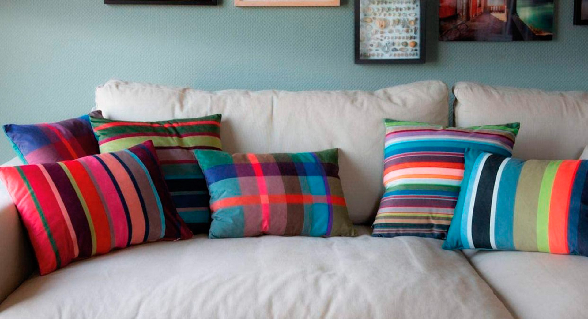 Kissen Costa Rossa in der Größe 50x35 Zentimeter der Marke Remember in Rottönen aus Polyester in einem Arrangement aus mehreren Dekokissen auf einer grauen Couch