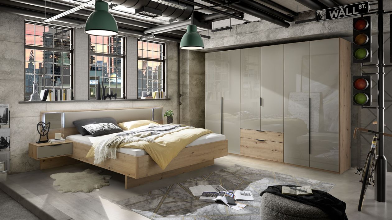 Industriell gestaltetes Schlafzimmer mit Holz-Doppelbett, Kleiderschrank, großen Fenstern, grünen Pendelleuchten und urbanem Dekor.