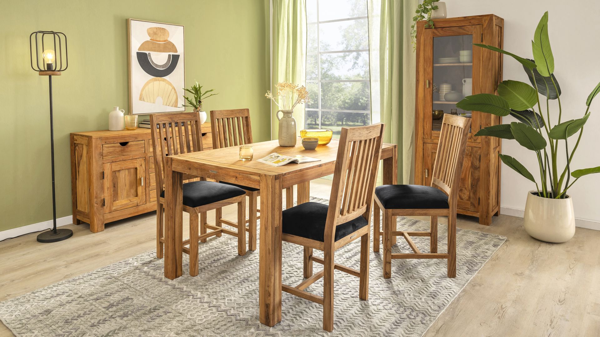 Ein Speisezimmer mit Massivholzmöbeln der Serie Yoga von Wolf Möbel. Zu sehen ist unter anderem der Esstisch Yoga aus Sheeshamholz und Stühle der Serie mit schwarzen Mikrofaserbezügen.