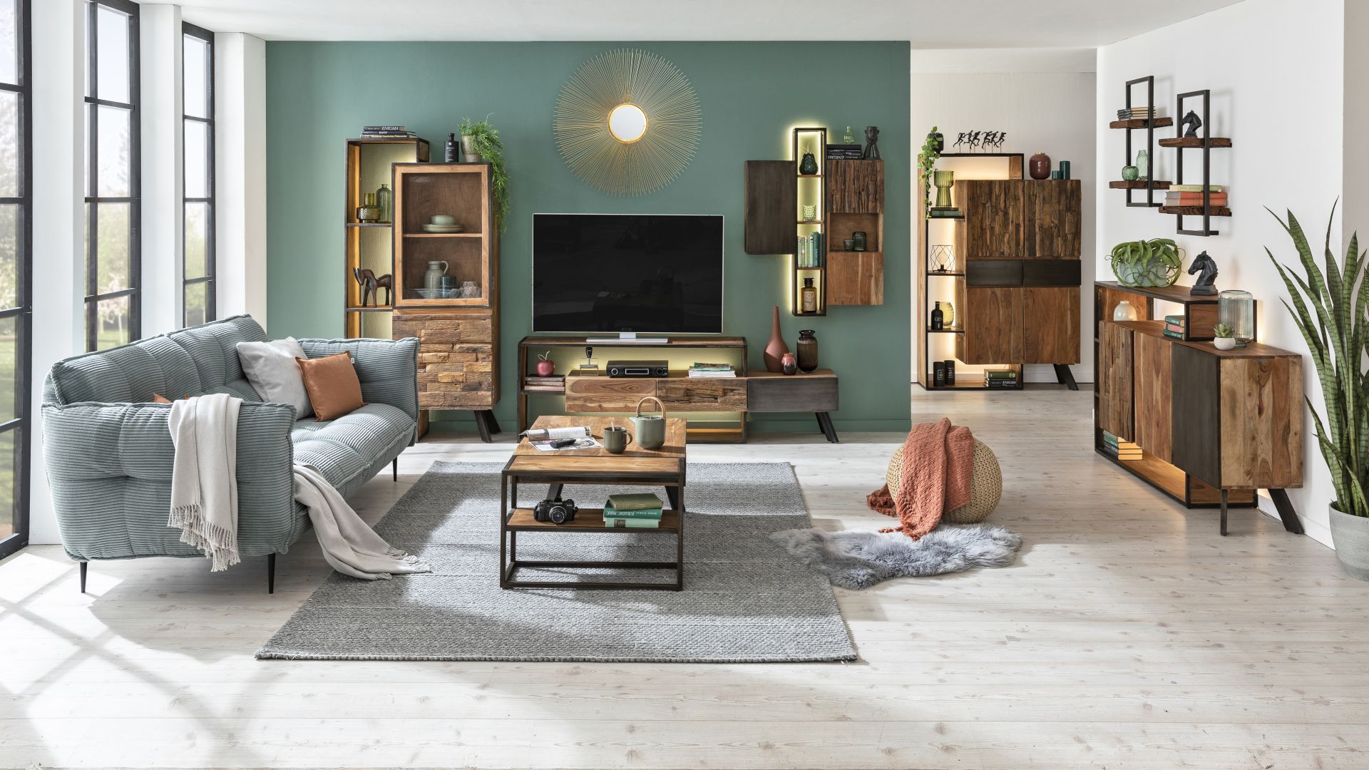 Ein modernes Wohnzimmer mit Massivholzmöbeln der Serie City von Wolf Möbel. Zu sehen sind unter anderem der Couchtisch City mit 2 Schubladen und einem eigenen kleinen Bücherregal und das Sideboard City 7529 aus Akazie und mit einem Eisengestell.