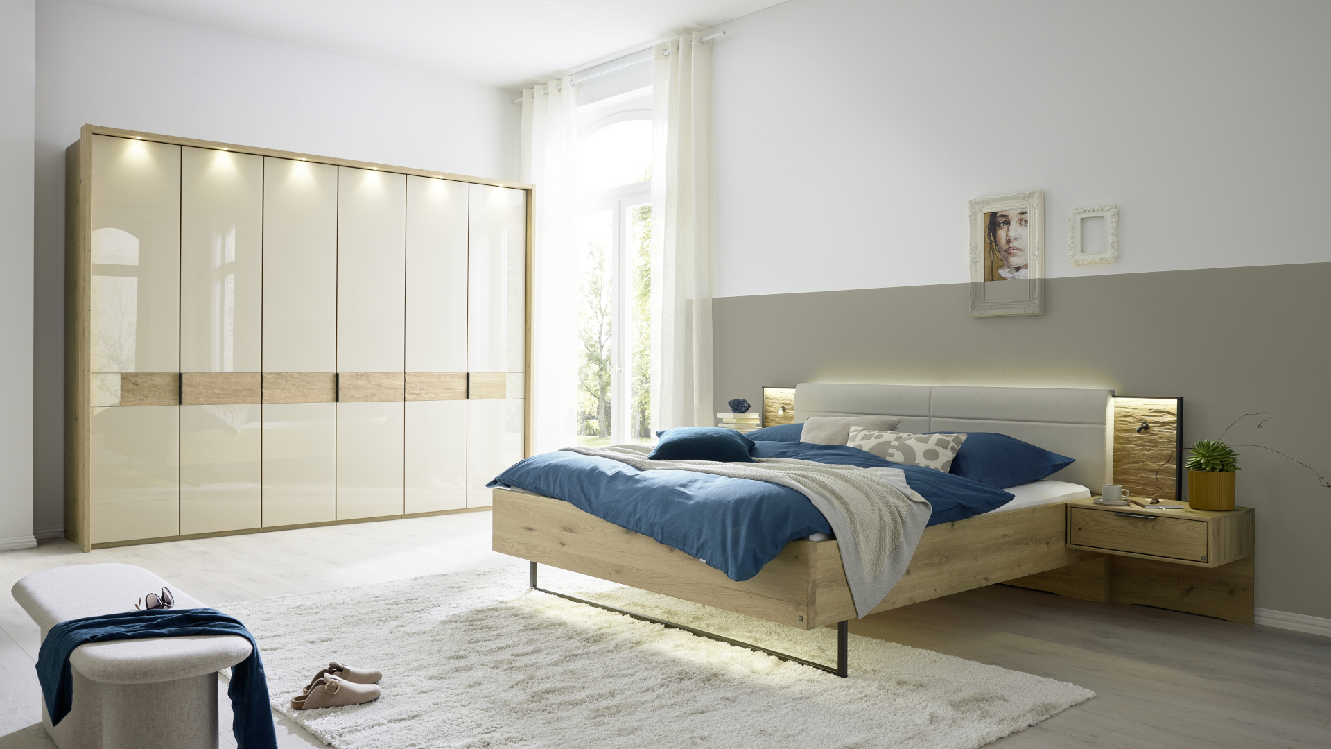 Das helle Schlafzimmer-Set San Francisco von Musterring mit einem großen Schrank mit Glastüren in Champagner und Holzelementen in Bianco- Eiche