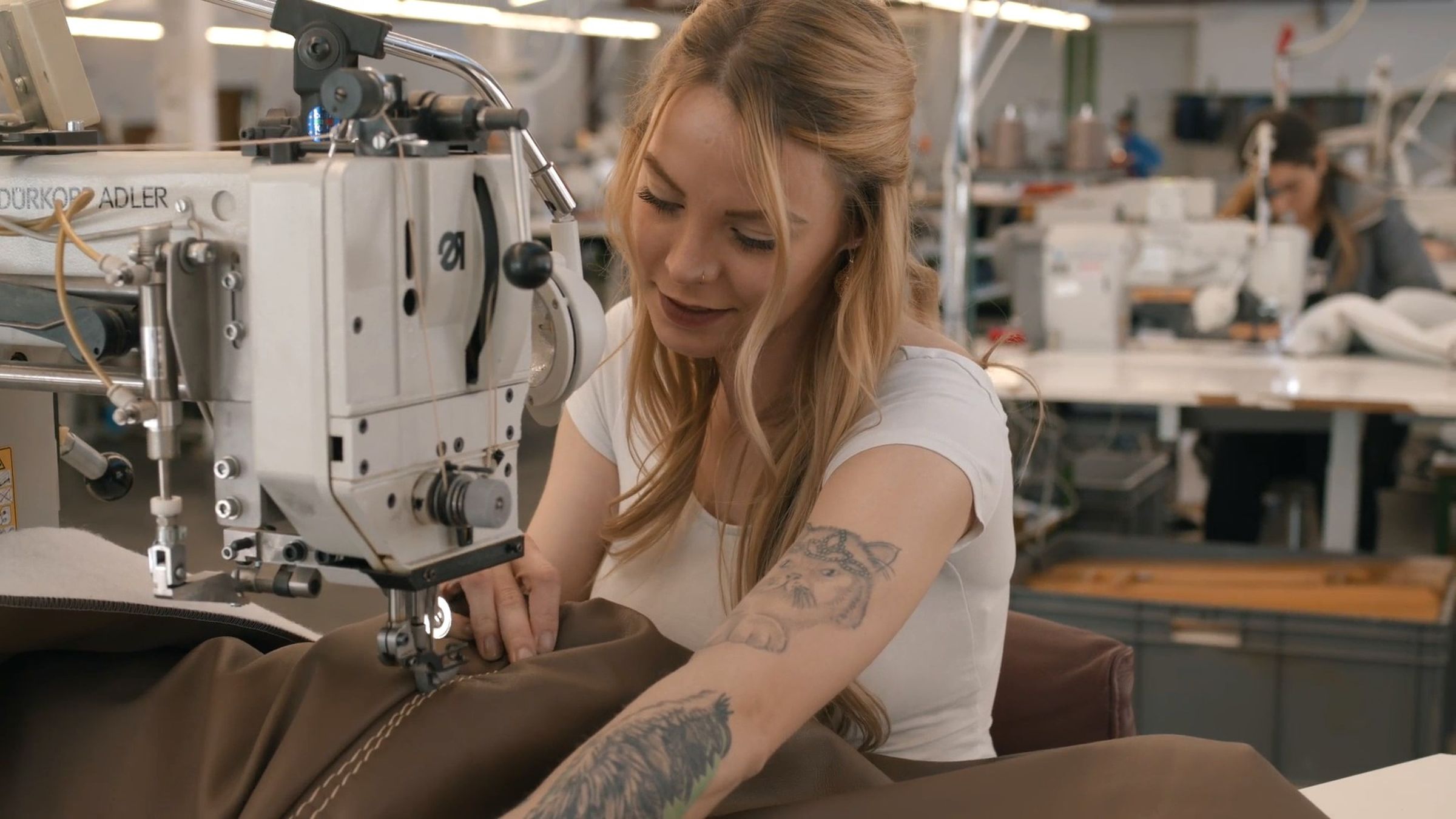 Eine Näherin arbeitet an einem dunkelbraunen Lederbezug.