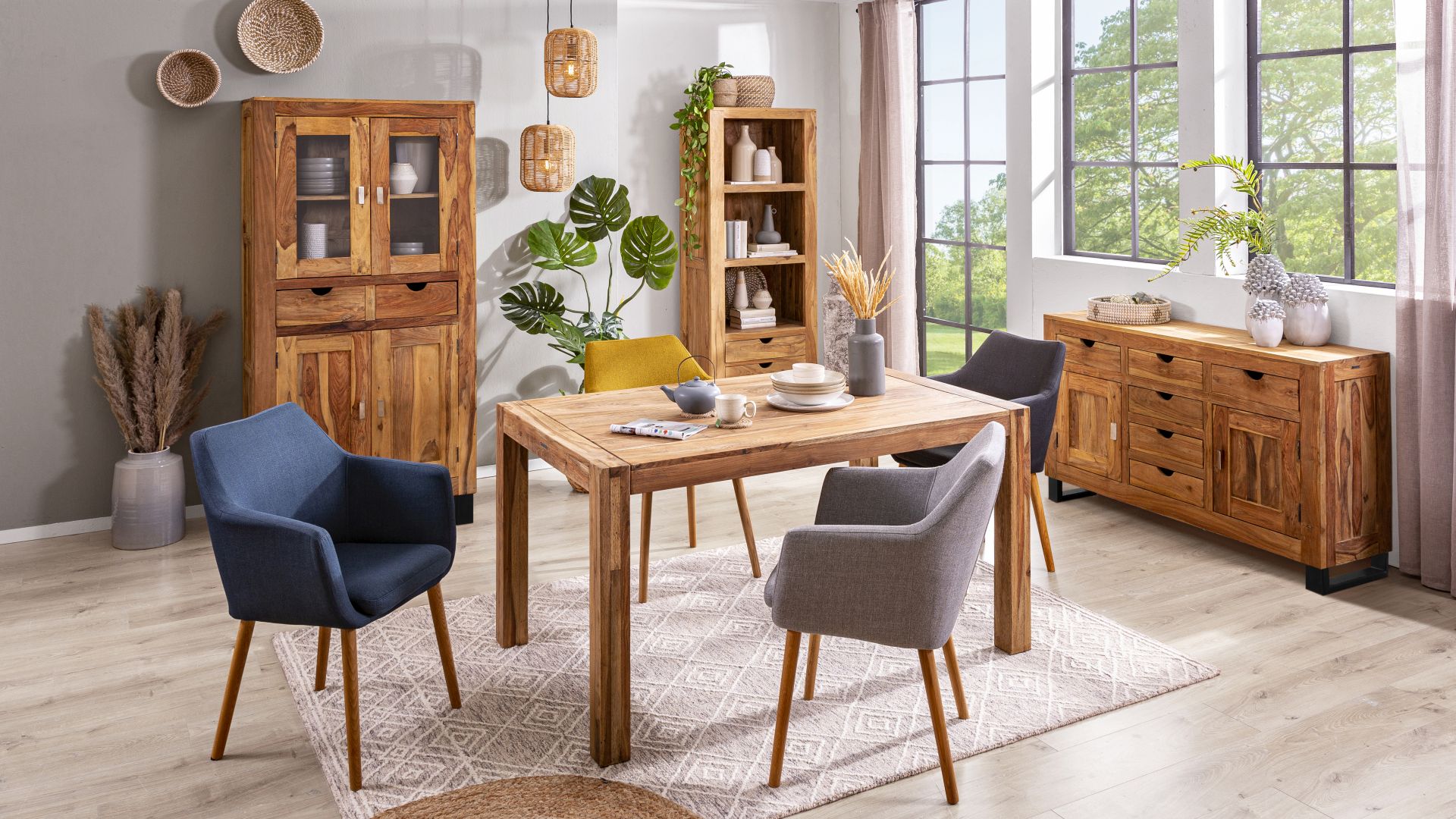 Ein Speisezimmer mit Massivholzmöbeln der Serie Yoga von Wolf Möbel. Zu sehen sind unter anderem die Vitrine Yoga aus Sheeshamholz mit 2 Glastüren und der Esstisch Yoga aus Sheeshamholz in den Maßen 140 x 90 cm.