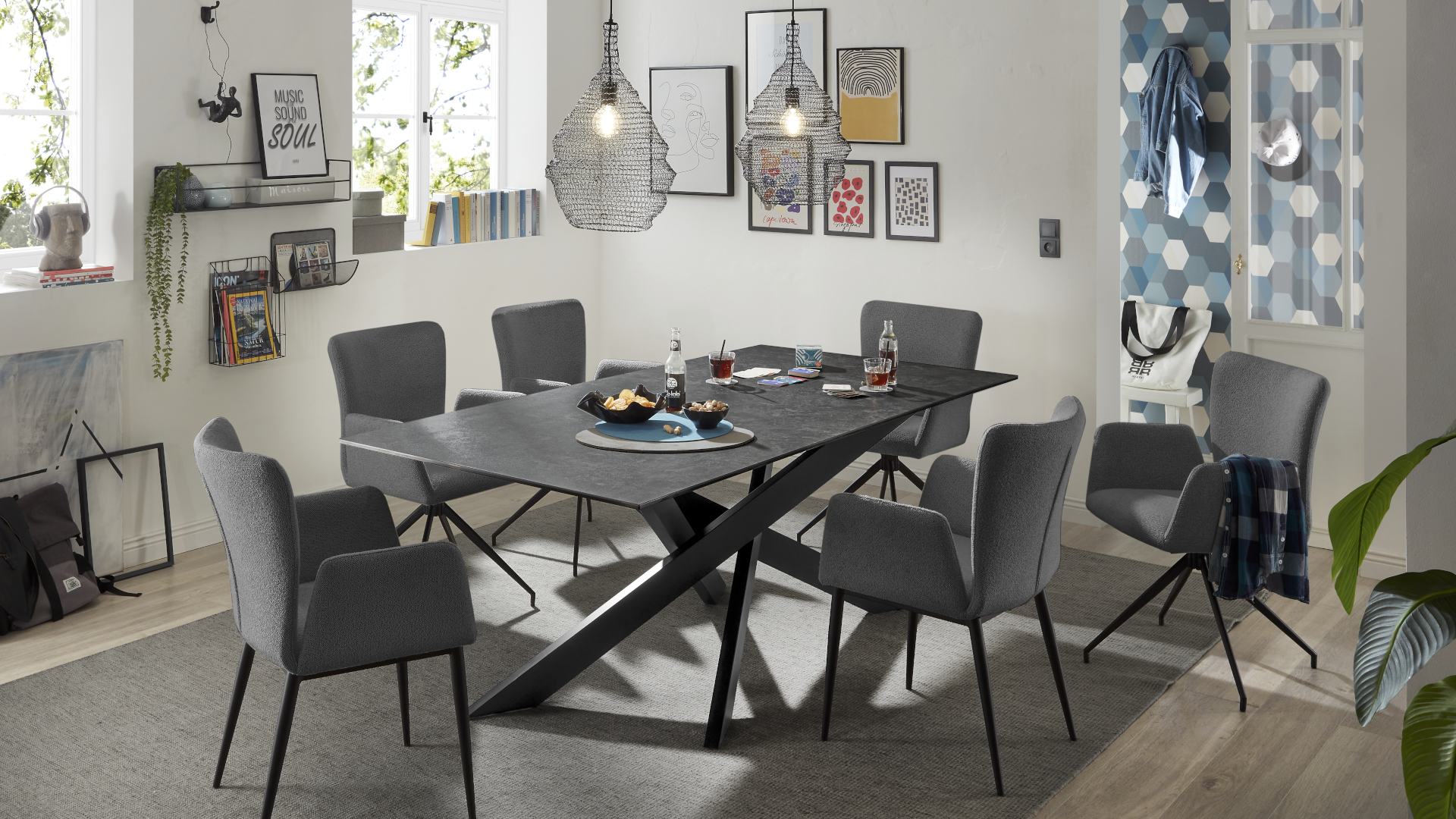 Ein schwarz-weißes Esszimmer mit Möbeln der Marke set one by Musterring. Zu sehen sind der Esstisch Baltimore in Schwarz mit einer Keramikplatte und Stühle des Modells El Paso mit Bouclébezug in Anthrazit.