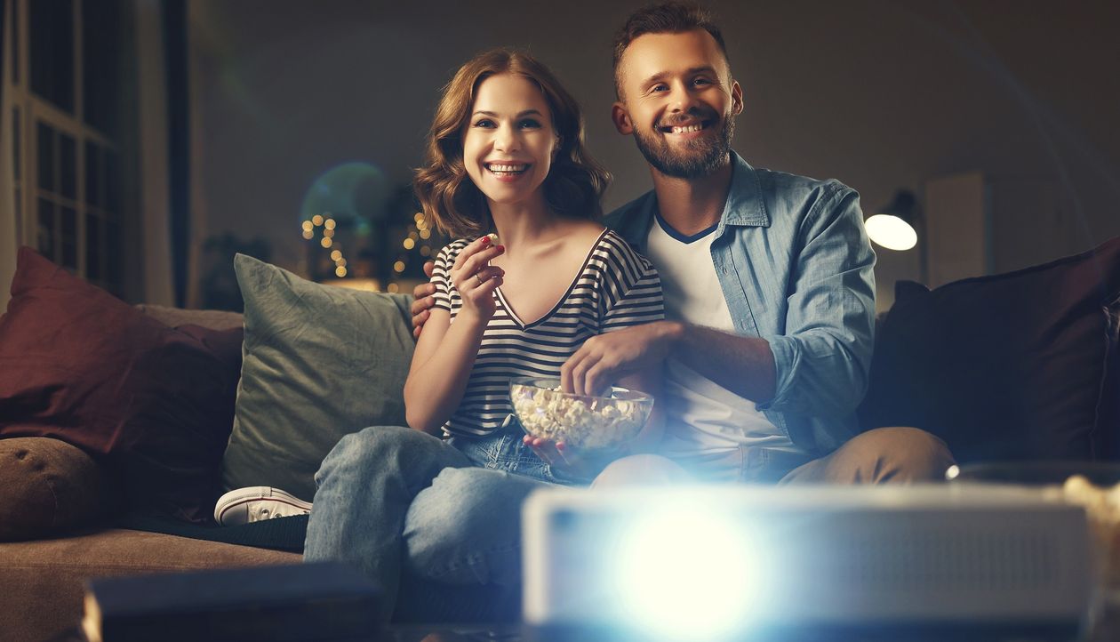 AdobeStock Foto eines Pärchens, die zuhause Kinoabends mit Popcorn veranstalten