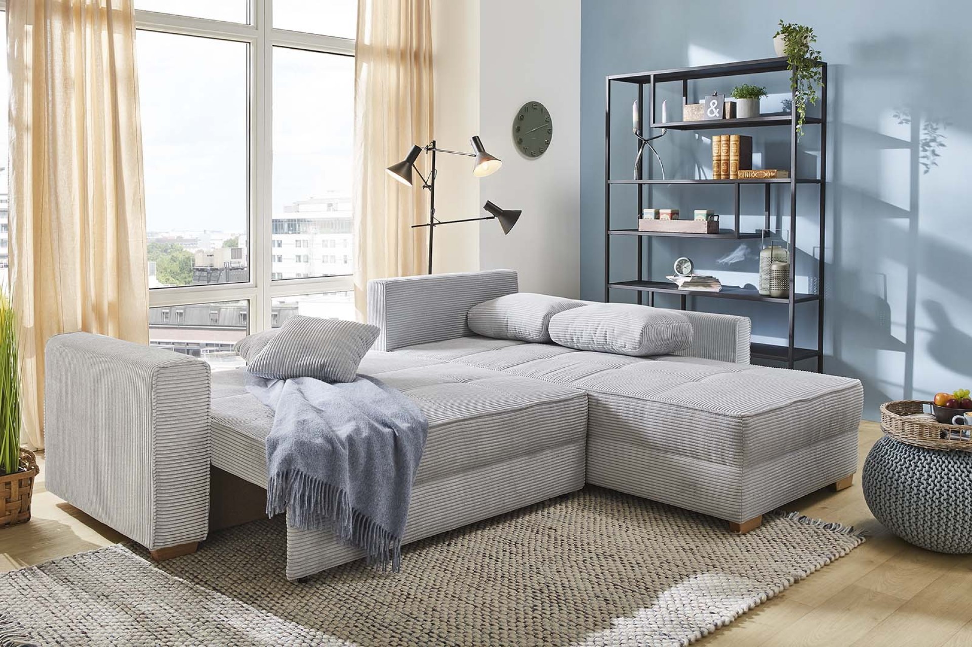 Ecksofa Jamell mit grauem Cordbezug mit Schlafoption durch umklappbarer Rückenlehne und ausziehbarer Sitzfläche in einem modernen Wohnzimmer