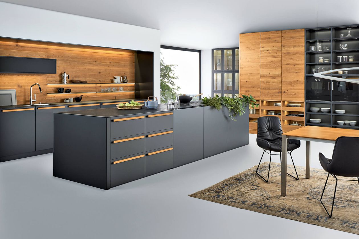 Moderne Küche mit eleganten grauen Schränken, Holzakzenten, großer Kochinsel, Essbereich, offenen Regalen und dekorativen Pflanzen.