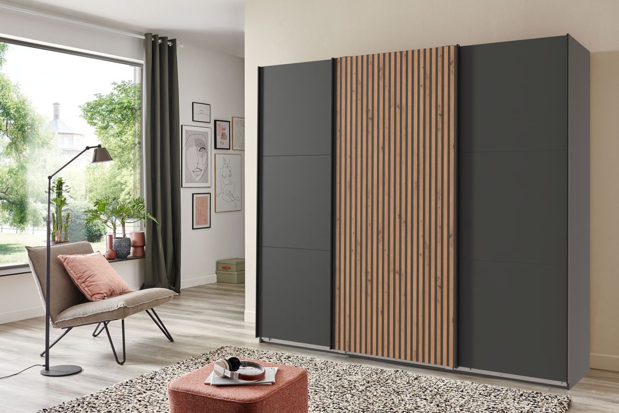 Der Schwebetürenschrank Andorra der Marke WIMEX mit einem Korpus in Graphit und einer Absetzung aus Akustikpaneelen in Eiche