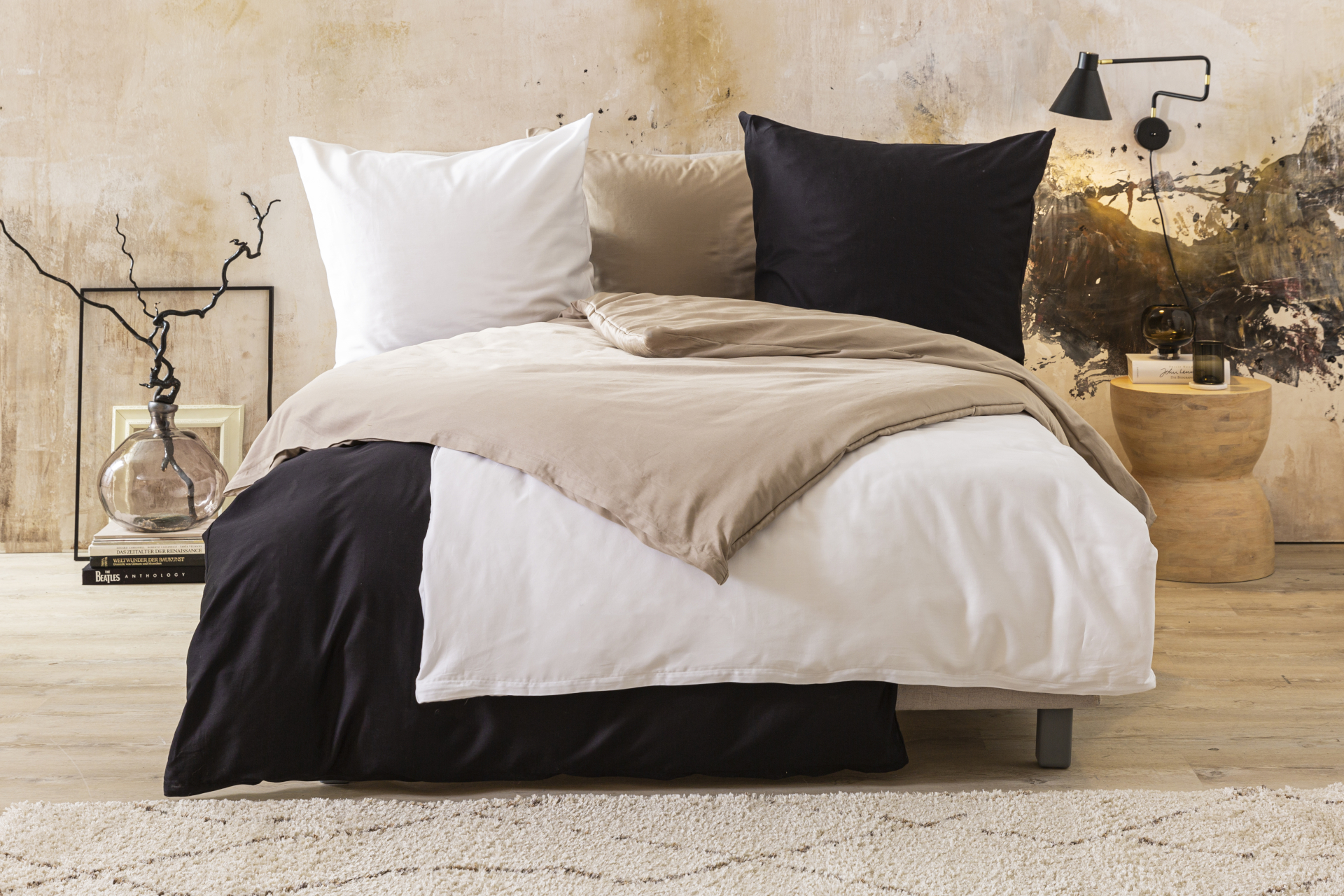 Die Satin-Bettwäsche Anna von Fürstenhof in Weiß, Creme und Anthrazit auf einem Bett