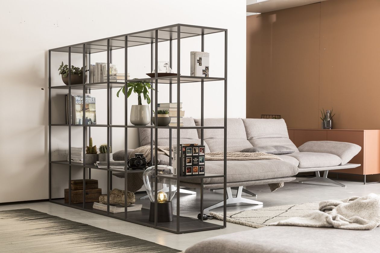 Produktbild: Schwarzes Regal als Raumtrenner neben grauem Sofa