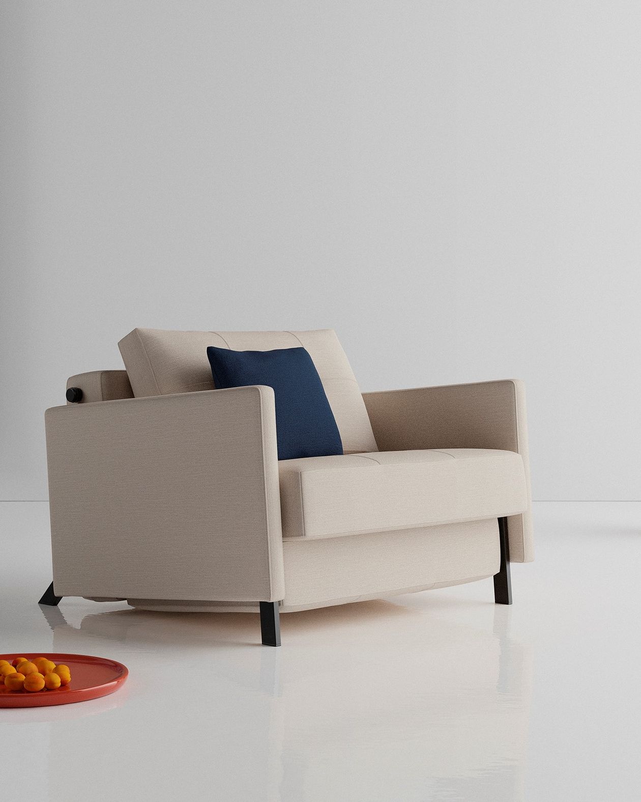 Auf dem Foto befindet sich ein beiger Schlafsessel im eingeklappten Zustand mit einem marineblauen Kissen.