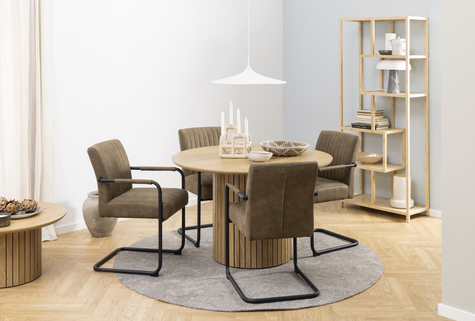 Freischwinger Adele von Actona aus hellbraunem Stoff an einem runden Tisch in modernem Design.