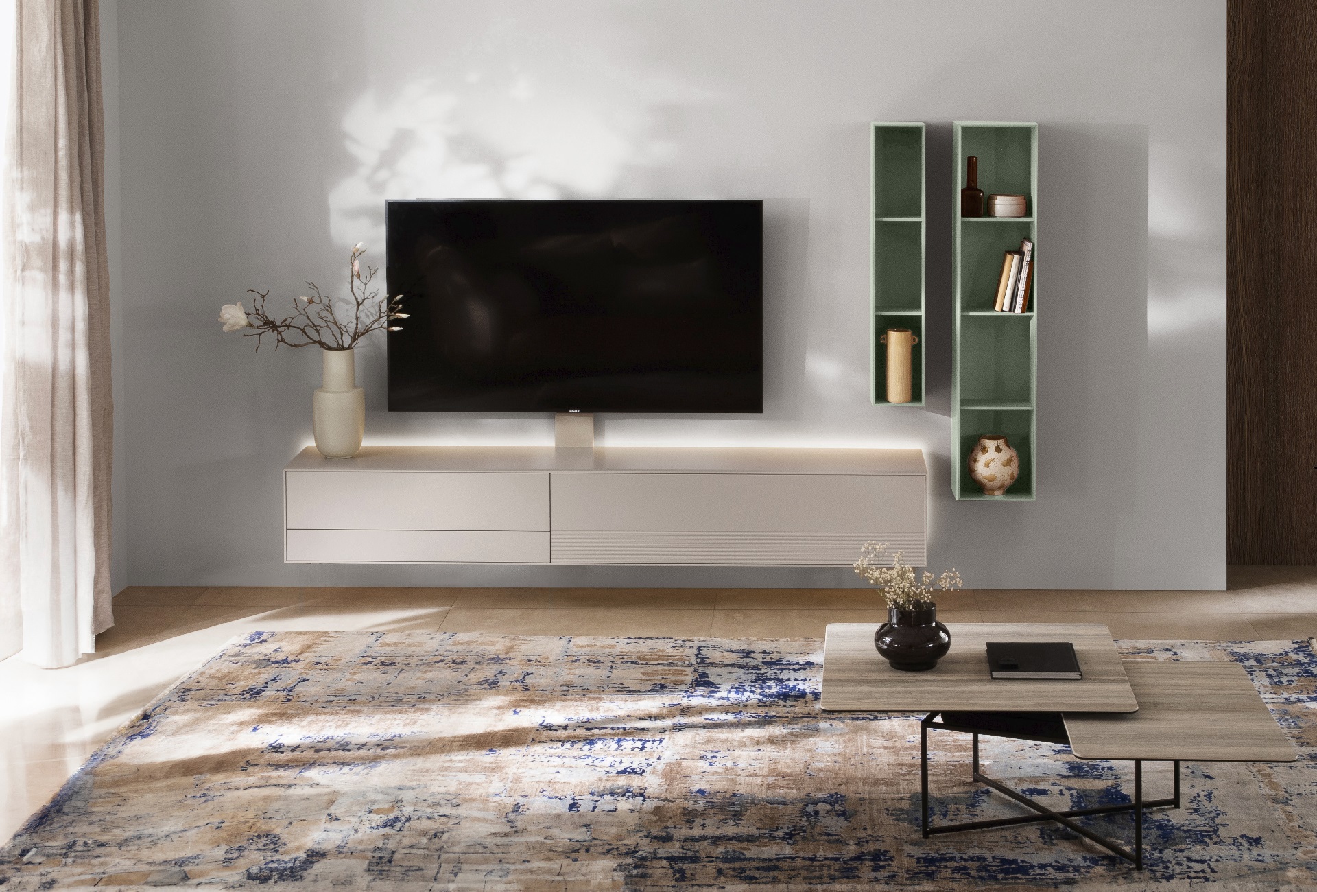 Moderne Wohnwand der Marke Sormani mit indirekter Beleuchtung in Weiß- und Grüntönen. Ein moderne Vintage-Teppich schafft Gemütlichkeit.