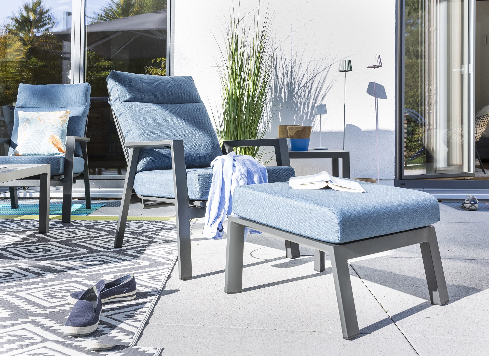 Gartenhocker Deluxe Lounge aus Aluminium mit blauen Kissen auf einer sommerlichen Terrasse