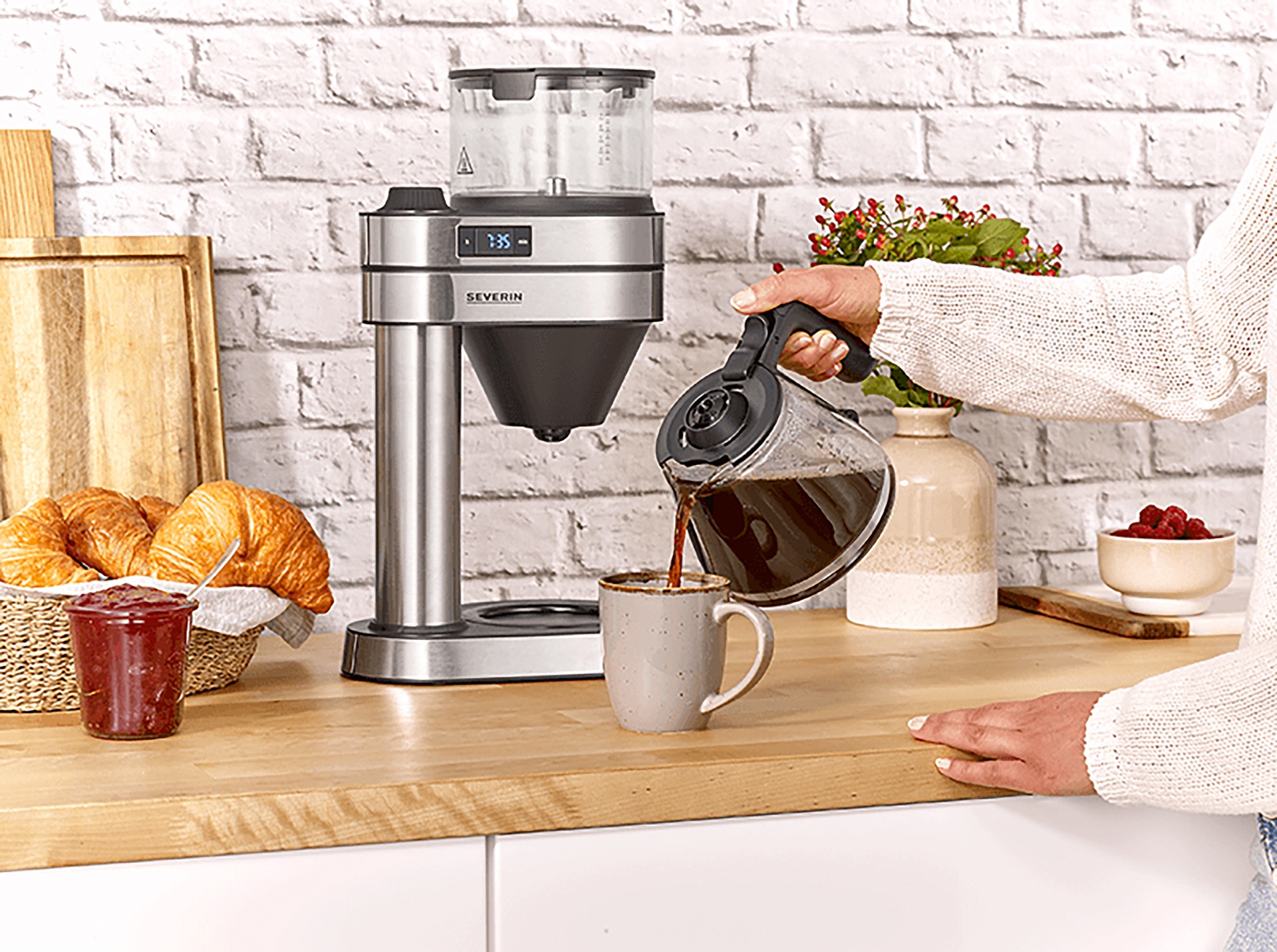 Kaffeemaschine Cafe Caprice in Silber aus Edelstahl zur Herstellung von Filterkaffee auf einem Küchentresen mit Frühstücksarrangement